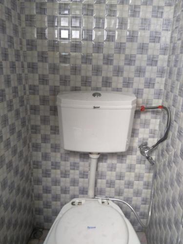 a white toilet in a bathroom with a tiled wall at Atathi Niwas Guest House for Backpackers and Travellers in Siliguri