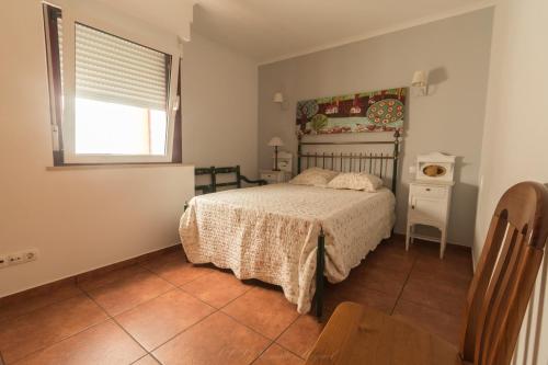 a bedroom with a bed and a window and a table at APARTAMENTO TELHEIRO in Vila Nova de Milfontes