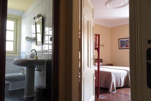 uma casa de banho com um lavatório, uma banheira e uma cama em Hostal Esmeralda em Comillas