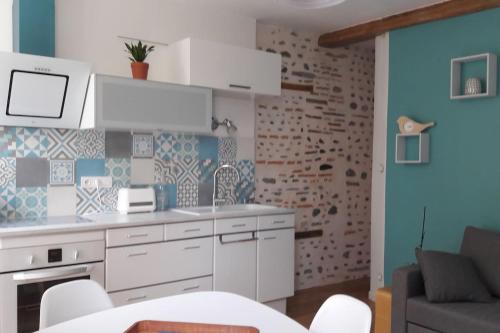 Un appartement lumineux au parc beaumont في بو: مطبخ فيه دواليب بيضاء وحائط ازرق
