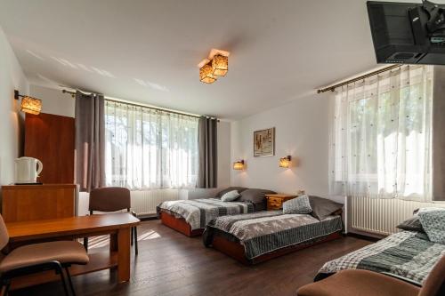 een woonkamer met twee bedden en een bank bij Willa Arkadia in Pobierowo