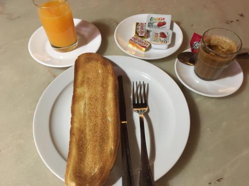 Ein Teller mit einem Stück Brot auf einem Tisch mit Getränken in der Unterkunft Hostal Moraleda ** in Piedrabuena