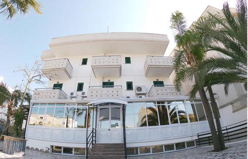 a large white building with palm trees in front of it at Porto Cesareo Hotel in Porto Cesareo