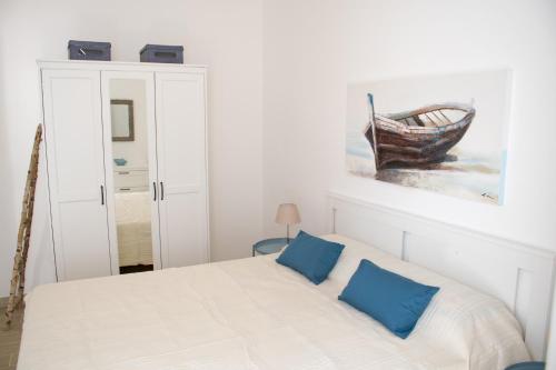 una camera bianca con letto e cuscini blu di Casa Vacanze Mondello Mare Piscina ALBAMAOR a Mondello