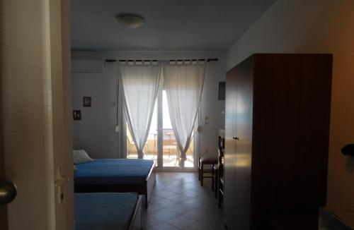 a bedroom with a bed and a door to a window at Studios Stefania in Neos Marmaras