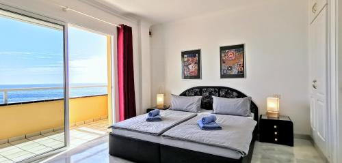 1 dormitorio con cama y ventana grande en Vitacrab Penthouse in erster Meereslinie, en Puerto de Santiago