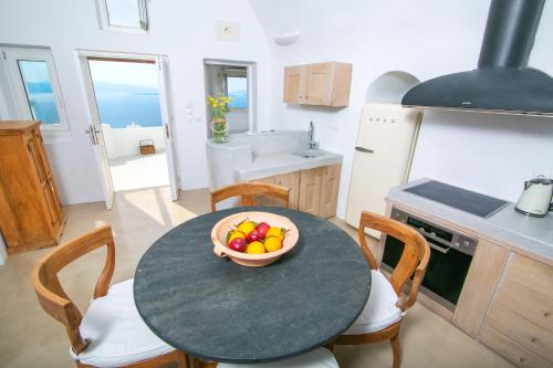 a kitchen with a table with a bowl of fruit on it at Menias Cave House in Oia