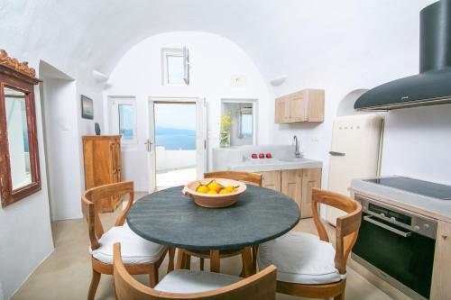 a kitchen with a table with a bowl of fruit on it at Menias Cave House in Oia