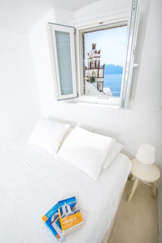 a bedroom with a bed and a window with a book at Menias Cave House in Oia