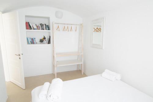 a white bedroom with a bed and a book shelf at Menias Cave House in Oia