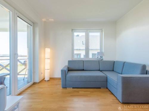 a living room with a blue couch and a window at Sterla - Masuria in Giżycko