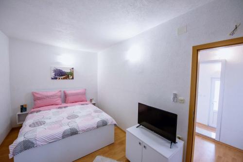 a bedroom with a bed and a flat screen tv at Apartman Sea view in Brist