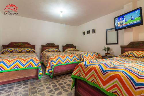 a room with three beds and a flat screen tv at Hotel La Casona in Jardin