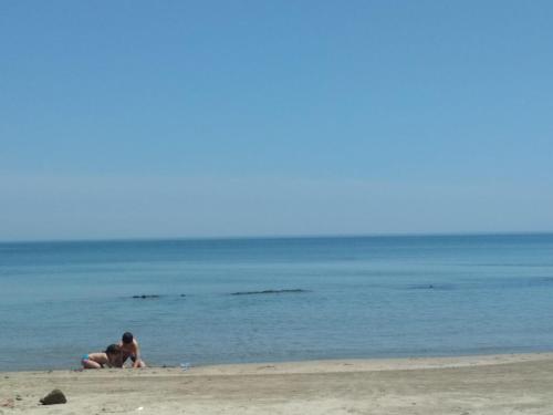 two people sitting on the beach near the water at Parus 4 Studio in Pomorie