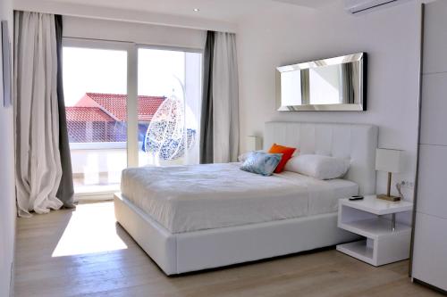 a white bedroom with a bed and a large window at Villa Mel II in Drasnice