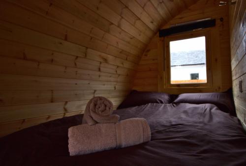 a bed in a log cabin with a towel on it at Coe Pod, West Highland Way Holidays in Kinlochleven