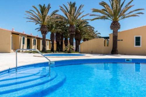 una gran piscina con palmeras y un edificio en Apartamento 7 Palmeras en Ciutadella