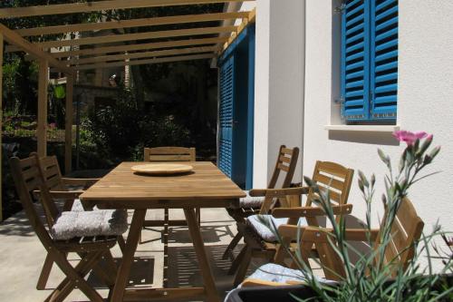 a wooden table and chairs on a patio with blue shutters at Mendula in Premantura