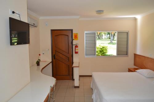 a hotel room with two beds and a window at Hotel Lago das Pedras in Apucarana