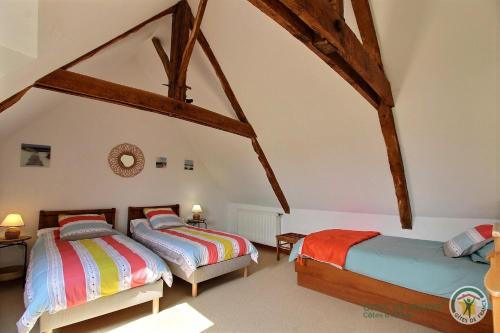 two beds in a attic room with wooden beams at MANOIR DE BOTMINY LAC de GUERLEDAN in Caurel