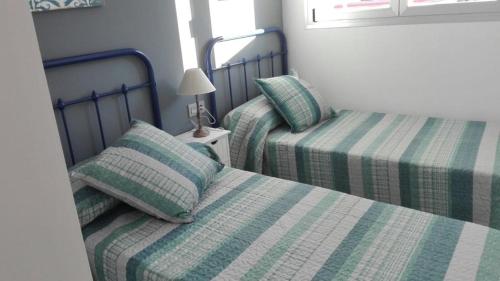 2 camas con sábanas verdes y blancas en una habitación en Edificio Attikos, en Playa de Gandía