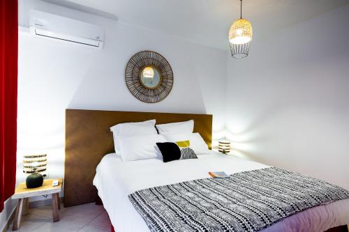 Appart Hotel Martinique - Mellow Yellow في Ducos: غرفة نوم مع سرير أبيض مع اللوح الأمامي البني