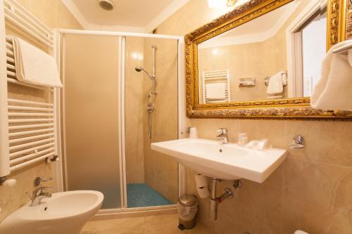 a bathroom with a sink and a shower with a mirror at Hotel Diplomat Palace in Rimini
