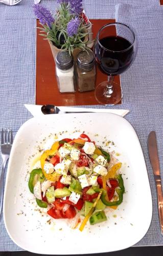 a plate of food on a table with a glass of wine at Grand Olympic Hotel Loutraki in Loutraki