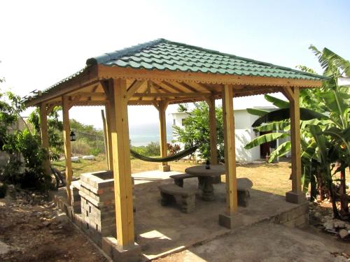 a wooden gazebo with a bench and a hose at Sunshine Lodge: Your home away from home in Montego Bay