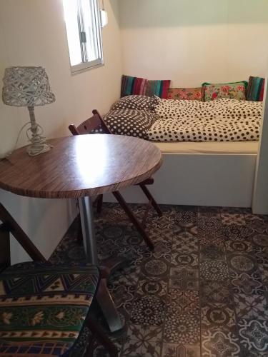 a living room with a table and a bed at Tinyhouse NATUURHUISJE met veranda Bij de Molen tussen Alkmaar en Hoorn in Oterleek