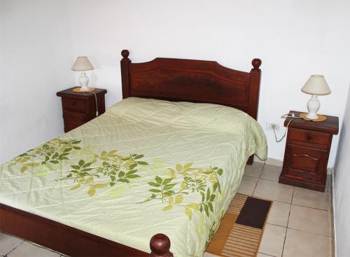 a bed with a green comforter and two night stands at Complejo Kalifornia in Pilar