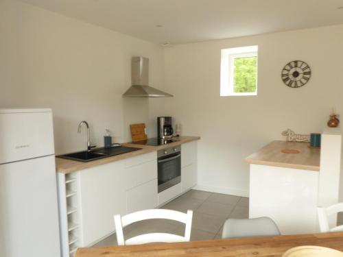 une cuisine avec des armoires blanches et une table et des chaises dans l'établissement Le Stepharion, à La Gaubretière