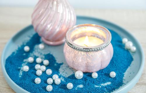 a candle sitting on a blue plate with beads at Ferienwohnung Narzisse - City Appartement im Kurpark Bad Aussee in Bad Aussee