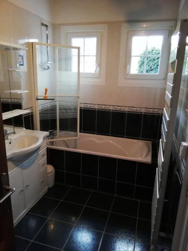 une salle de bain avec une baignoire et un lavabo dans l'établissement Les Mésanges, à Fort-Mahon-Plage