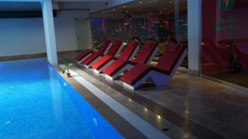 uma fila de cadeiras vermelhas ao lado de uma piscina em My Palace Rooms Hotel SAW em Istambul
