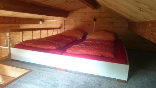 a bed in a wooden cabin with red sheets at Kleine Auszeit in Waren