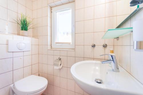 a bathroom with a sink and a toilet and a window at Ferienbungalow Fischerstrand in Binz