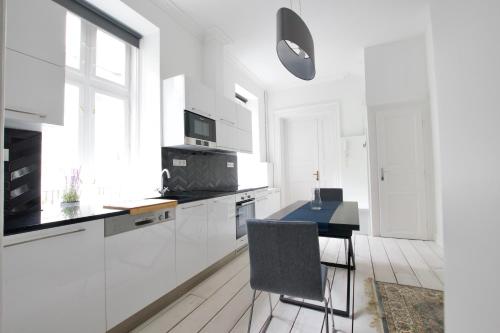 a kitchen with white cabinets and a table with a chair at Luxury Apartment by Hi5 - Október 6 Street in Budapest