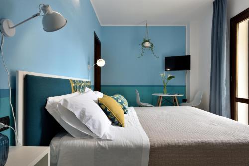 1 dormitorio con 1 cama con pared azul en La Tortorella Room & Apartment en Tortolì