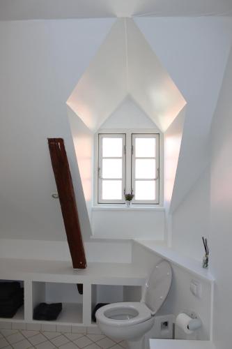 a white bathroom with a toilet and a window at Kildegaarden in Kokkedal