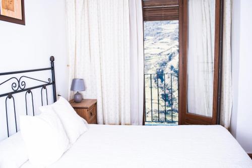 a bedroom with a white bed and a window at Apartamentos Vista Veleta in Capileira