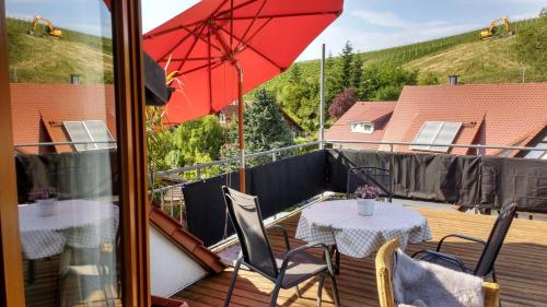 a balcony with two tables and a red umbrella at Haus Rebblick in Offenburg