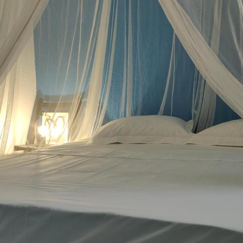 un letto con baldacchino con cuscini bianchi di Escale Caraibes a Trois-Rivières