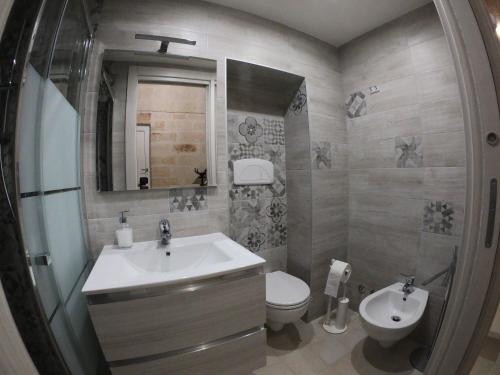 bagno con lavandino, servizi igienici e specchio di casa principe di napoli a Polignano a Mare