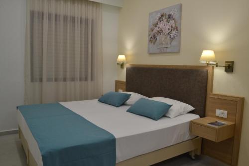 a bedroom with a large bed with two blue pillows at Romantica Apartments in Falasarna