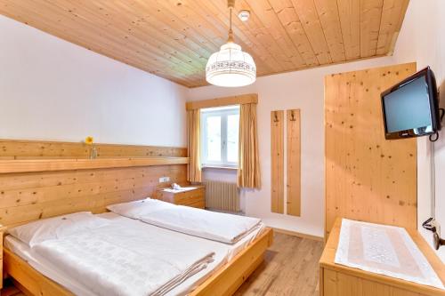 um quarto com uma cama e uma televisão de ecrã plano em Garni Kircher Sepp em Barbiano