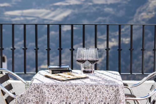 una mesa con 2 copas de vino en el balcón en Apartamentos Vista Veleta, en Capileira