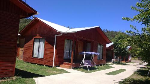 a wooden house with an umbrella in front of it at Cabañas Villa Rivas in Contulmo