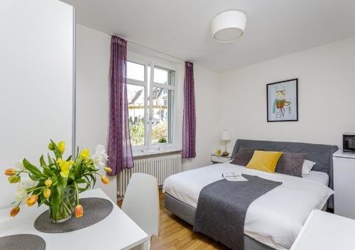 a bedroom with a bed and a table with a vase of flowers at Rent a Home Delsbergerallee - Self Check-In in Basel