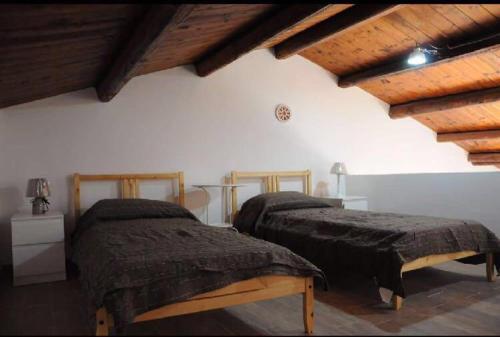 two beds in a room with wooden ceilings at DONNA FELICIA in Pachino